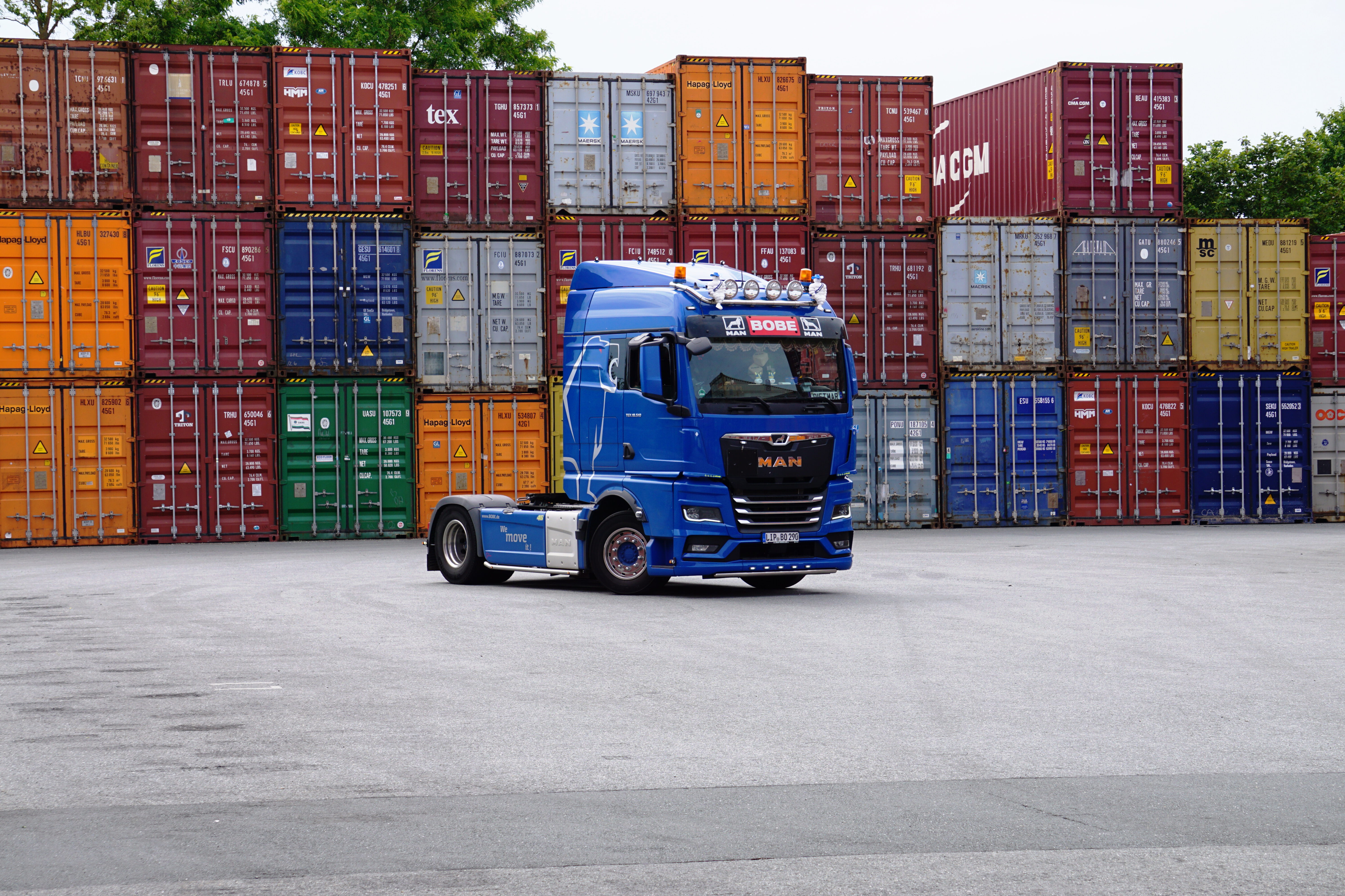 Ein Terminalgelände mit akkurat übereinander gestapelten Containern und einem blauen BOBE-LKW im Vordergrund – BOBE