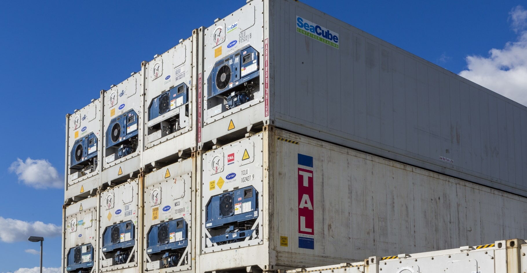 Mehrere weiß gestapelte Container mit Kühleinheiten unter blauem Himmel – BOBE