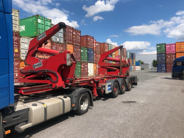 Ein blauer BOBE-LKW mit Seitenlader-Spezialauflieger hebt einen Container an bzw. steht bereit auf dem Terminalgelände – BOBE