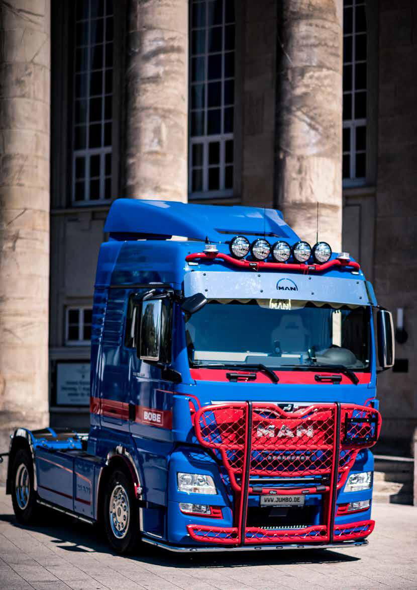 Blau-roter MAN Lkw mit BOBE Aufbau und LED-Lichtern vor historischen Gebäuden – BOBE