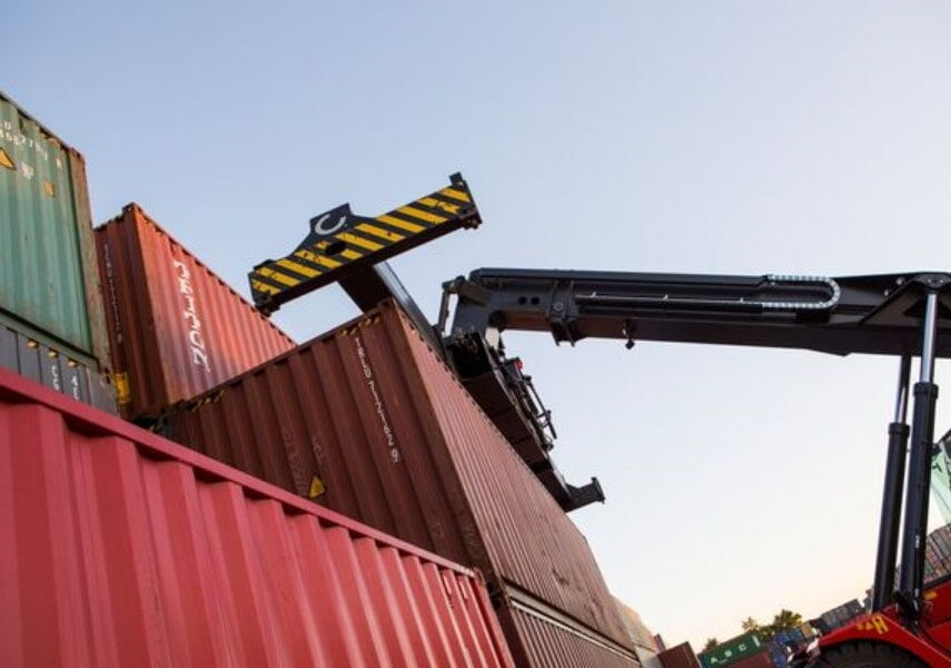 Detailaufnahme eines Greifarms beim Stapeln von Seecontainern im Depot