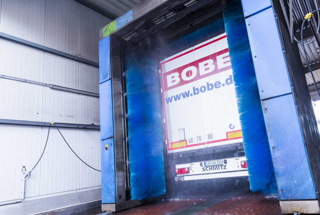 Ein BOBE-Auflieger durchläuft eine automatische Portalwaschanlage mit blauen Bürsten – BOBE