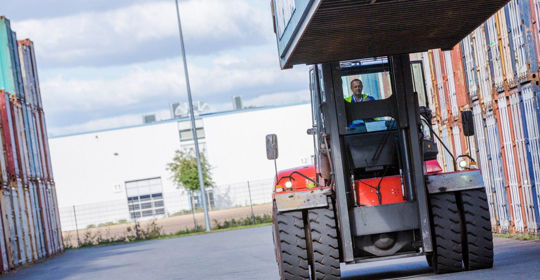 Ein Stapler hebt einen ISO-Container auf einem Lagerplatz zwischen Containerreihen an – BOBE