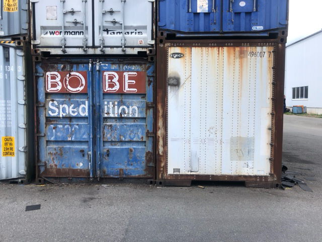 Ein älterer blauer Seecontainer mit dem BOBE Spedition Schriftzug steht neben anderen Containern auf dem Terminalgelände – BOBE