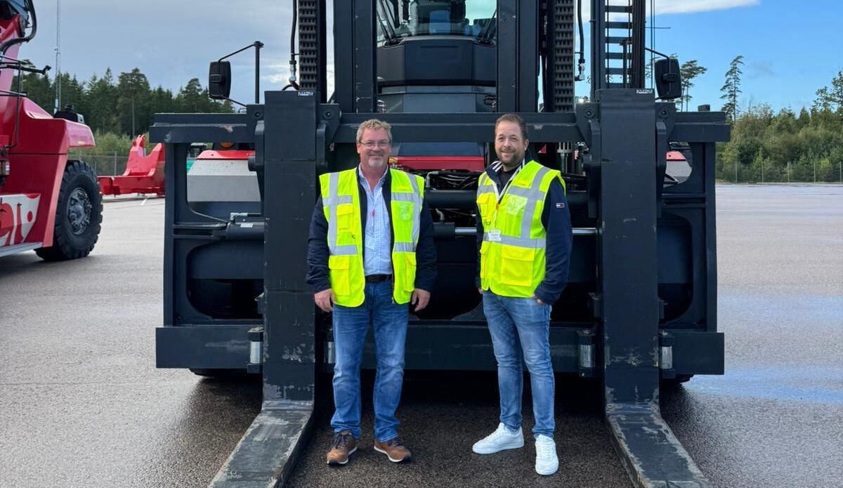 Zwei Mitarbeiter in Warnwesten stehen vor einem großen Gabelstapler auf dem Betriebsgelände – BOBE