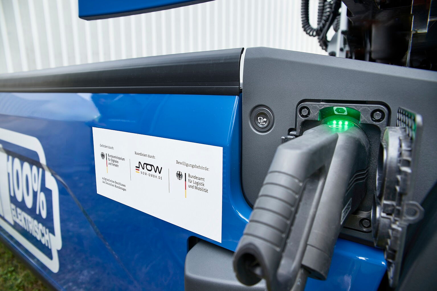 Nahaufnahme des Ladevorgangs an einem BOBE E-LKW mit Hinweisschild auf die Förderung durch das BMDV und die NOW GmbH – BOBE
