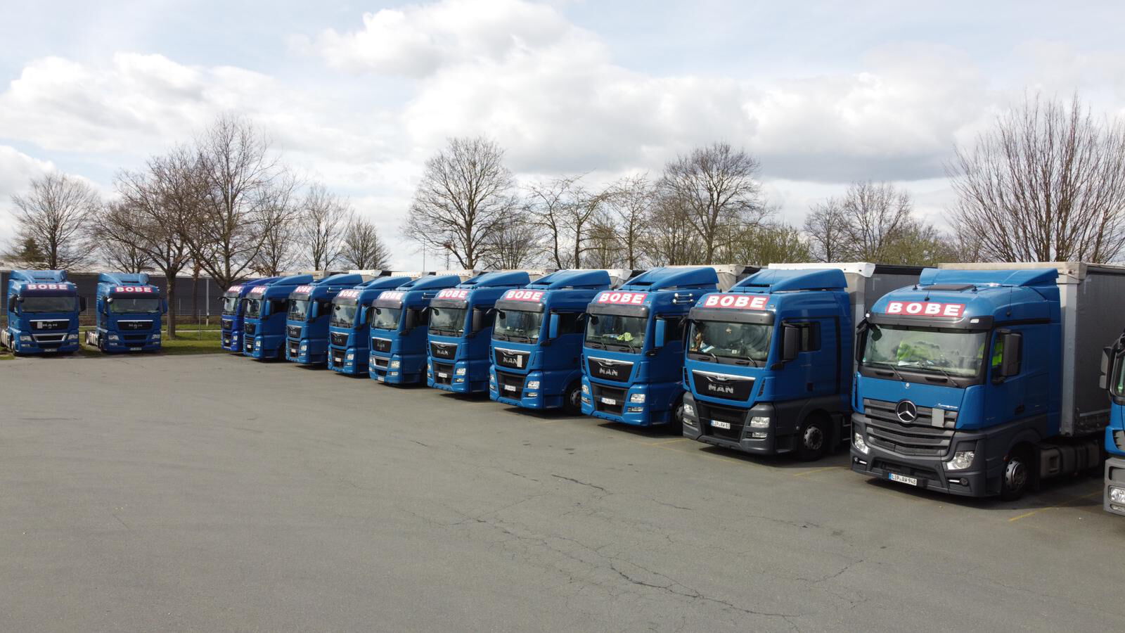 Eine lange Reihe blauer BOBE-LKWs steht ordentlich aufgereiht auf dem Betriebsgelände bereit für den Einsatz – BOBE