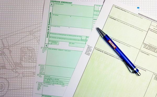 Ein blauer BOBE-Kugelschreiber liegt auf offiziellen Zollformularen für den grenzüberschreitenden Handel – BOBE